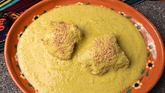 Traditional Mexican dinner featuring chicken with green mole or pipian and decorative clay dish, aerial view