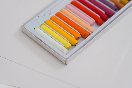 Set of oil pastels in box with white paper. Crayons
