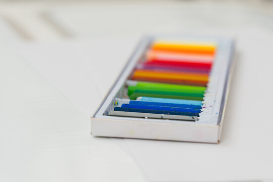 Set of oil pastels in box with white paper. Crayons