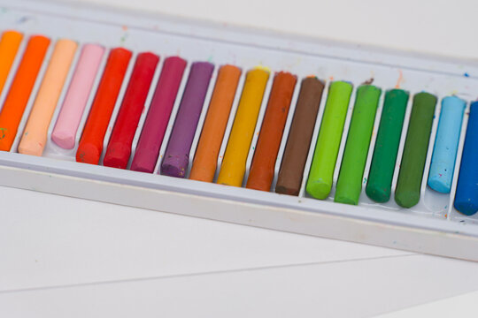 Set of oil pastels in box with white paper. Crayons