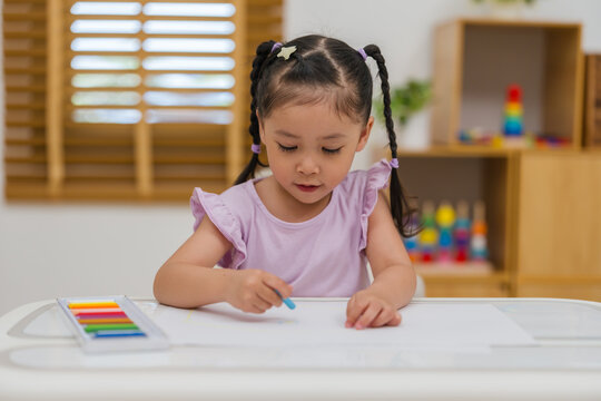 preschool child girl drawing and painting with colorful oil pastels on paper