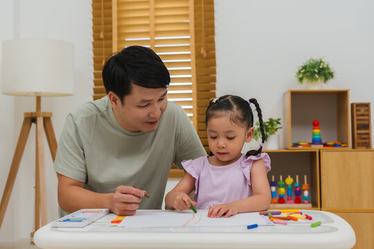 father and child girl drawing and painting with colorful oil pastels on paper
