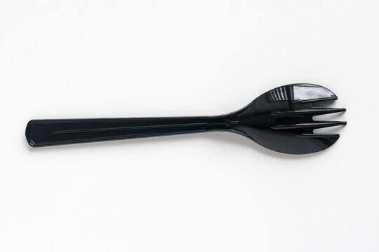 Closeup shot of a black spork in an upside-down position, isolated on a clean white background.