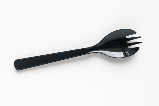 Closeup shot of a black spork in an upright position, isolated on a clean white background.