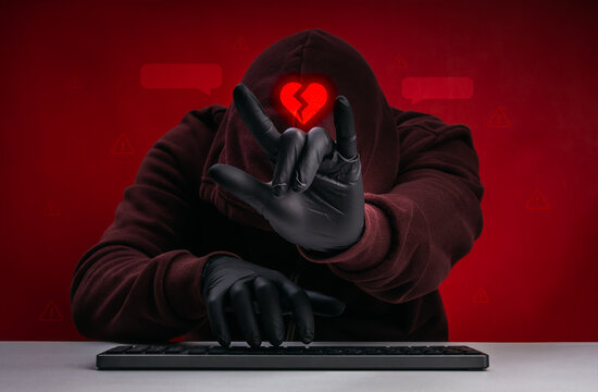 Romance scam and online deception concept with hooded cybercriminal and broken heart symbol. Emotional manipulation, love fraud warning, digital dating scam risk and social engineering attack.