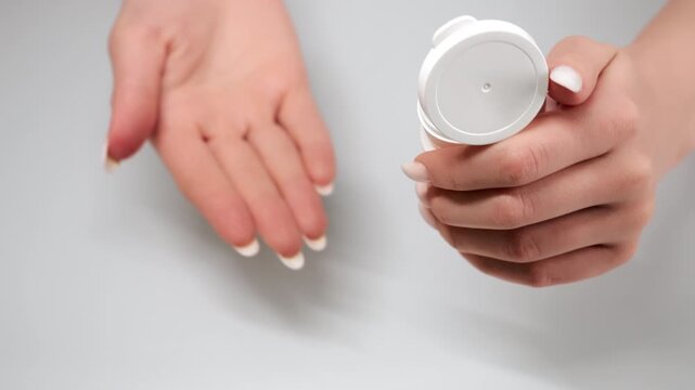 Close up of woman opening pill bottle and pouring capsules into hand in healthcare concept of medication treatment pharmacy and drug use.