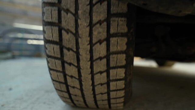 Car wheel with deep tire tread slowly rolling in slow motion close-up