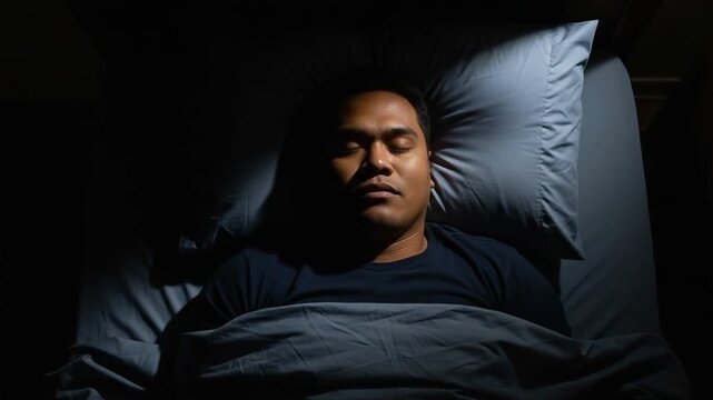 Peaceful Southeast Asian man resting in bed for deep REM sleep and circadian rhythm health