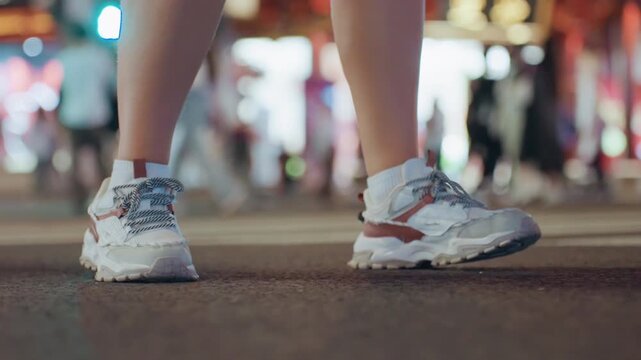 Lowangle sneakers stepping across neon crosswalk, energetic street dancer moving through bustling crowd, evening lights and reflections, rhythmic footwork and confident urban performance