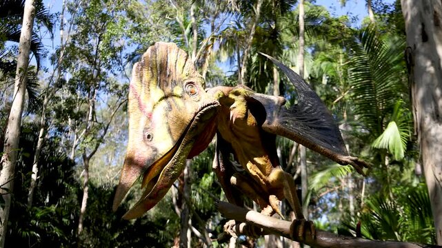 Pterodactyl Dinosaur Statue Perched on a Branch in a Lush Forest