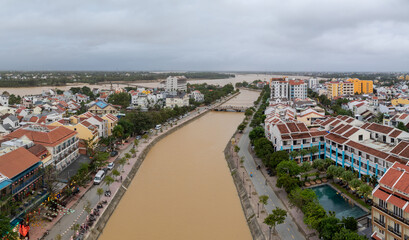 Fototapeta premium Aerial view of the Thu Bon River flowing through Hoi An Ancient Town, Vietnam. The river is high and muddy due to seasonal flooding in Quang Nam Province.