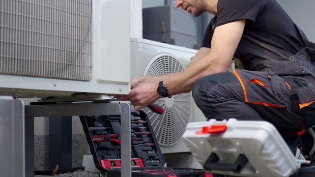 Technician servicing outdoor heat pump unit with tools beside residential house. Concept of HVAC maintenance home climate control and energy efficient heating and cooling