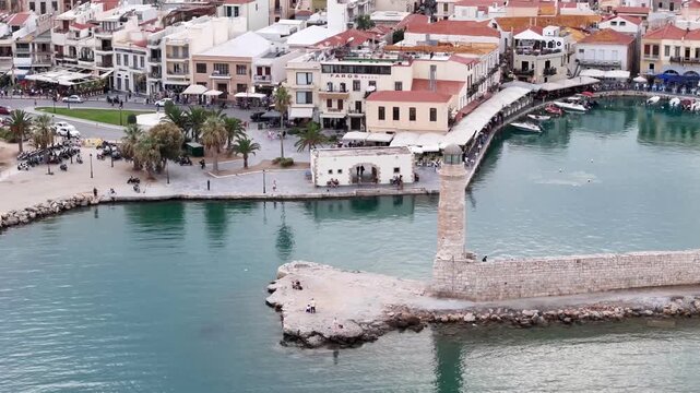Scenic aerial footage of the historic old venetian harbor with its iconic lighthouse in rethymno, crete