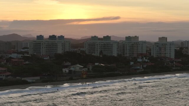Aerial view of Penha and Balneario Picarras coastline along Avenida Nereu Ramos and Avenida Itapocoroi, Santa Catarina, Brazil, with beachfront skyline and Atlantic Ocean at sunset.
