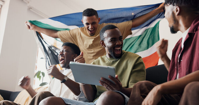 Soccer game, celebration and men in lounge, tablet and excited for score victory. Live streaming, champion and happy people in home, fans and fist pump for sports tournament or South African flag