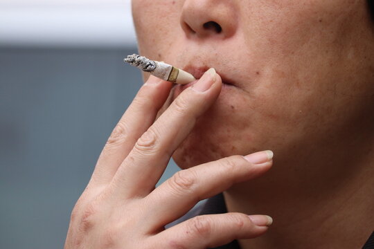 Close-up of a person smoking a nearly finished cigarette, highlighting nicotine addiction and stress relief behavior