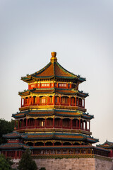 Obraz premium The Tower of Buddhist Incense (Foxiang Pavilion) at the Summer Palace in Beijing, China, rises above lush green trees under a clear summer sky.