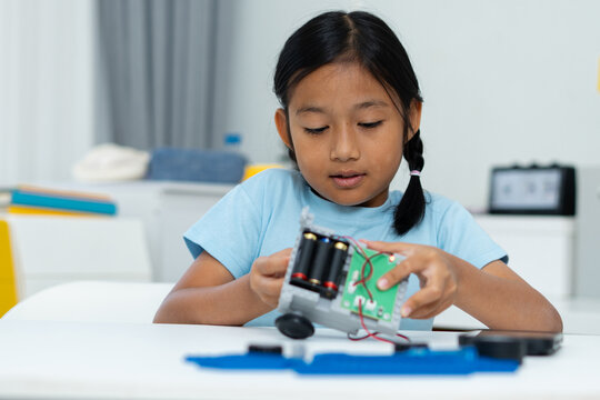 Young girl working on a robot design. Learning robotics basics.