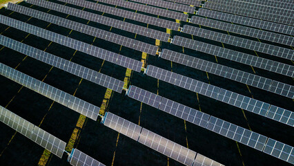 Obraz premium Aerial drone top view of solar farm with geometric rows of photovoltaic panels producing renewable energy