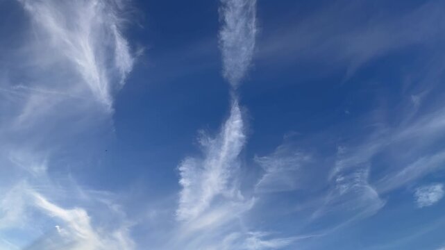 Time-lapse of feathery white clouds moving across blue sky