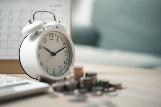 Alarm clock with coins and planner representing time-based budgeting, savings goals, and financial planning for effective money management.