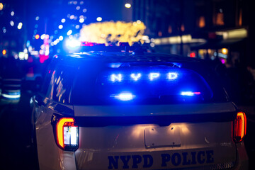 NYPD police car with flashing lights at night. NYPD police car parked on city street. NYPD police car responding to emergency. NYPD police car patrolling downtown. © Volodymyr