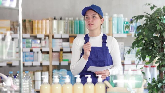In drugstore, builder woman with prescription looks at display cases, trying to find multivitamins for adults. Client looks at display cases, selects calcium supplement complex 