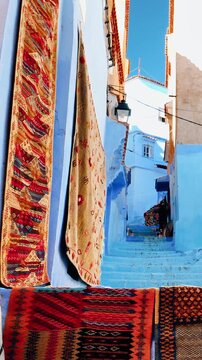 Vertical Scenic View of Chefchaouen Blue City Alley with Traditional Berber Rugs - Morocco