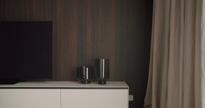 A stylish living room setup featuring a flat-screen TV, modern white cabinet, and elegant minimalist vases, creating a clean and contemporary design. Modern Living Room Interior with TV