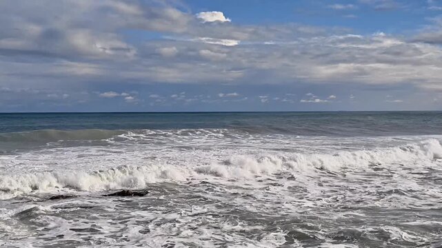white foam waves rolling across open ocean horizon, restless surf under soft clouds, energetic breakers