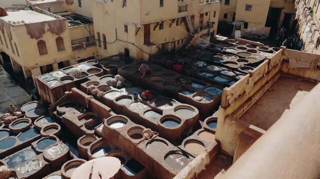Workers tanning leather hides in stone vats at Chouara Tannery in Fes, Morocco. The tannery is one of the oldest in the world and a popular tourist destination.