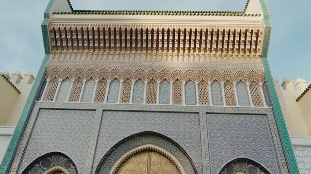 The Royal Palace in Fes, Morocco. Intricate Moroccan tile and mosaic work adorns the walls and large golden doors of the historic palace. Fes is one of the oldest imperial cities in Morocco.