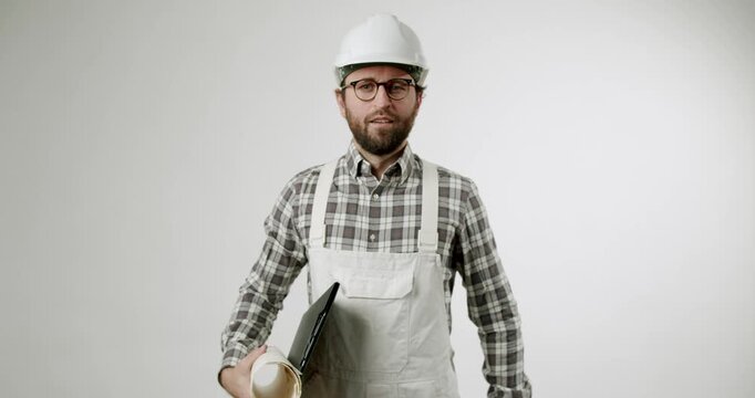 A confident construction worker or engineer walks in with blueprints and a clipboard. He looks directly at the camera and nods his head yes, signaling agreement. This video conveys professionalism,