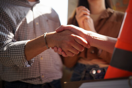 Homeowner shaking hands with a construction engineer after agreeing on a new house building project.