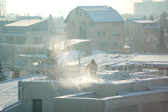 man clearing snow from the terrace of a house.