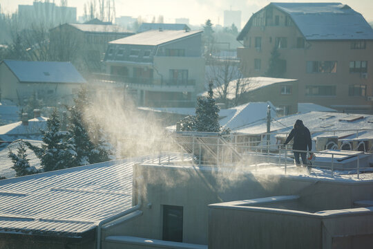 man clearing snow from the terrace of a house.