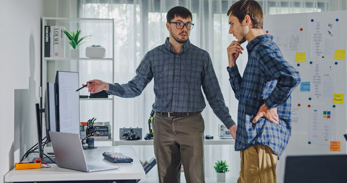Team adult male engineer collaborate on robotic hand project using AI code solutions machine learning at tech workspace. Artificial intelligence interface, collaboration support prototype development.