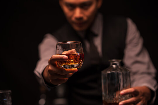 Bartender Holding Out a Glass of Premium Whiskey to Customer
