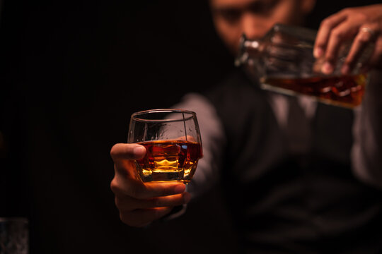 Bartender Holding Out a Glass of Premium Whiskey to Customer