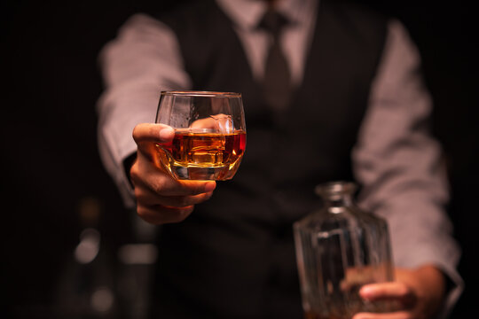 Bartender Holding Out a Glass of Premium Whiskey to Customer