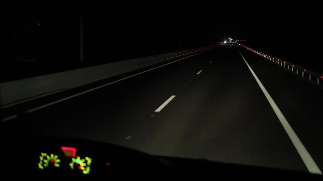 Dark highway illuminated by distant lights smooth road surface and guiding lines create strong sense of movement speed and endless night journey