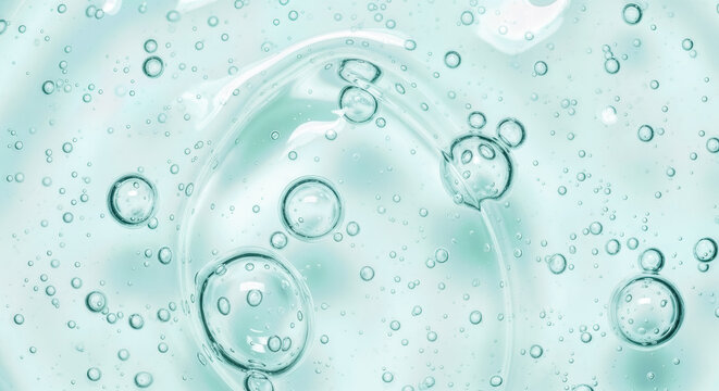 Transparent cosmetic gel texture with bubbles on light blue background, hydrating serum surface, hygiene liquid soap macro, clean skin care product
