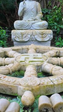 A serene Buddha statue sits among deer sculptures and a Dharma wheel in the gardens of The Marble Mountains, in DA NANG, Vietnam. The statues symbolize peace and harmony.