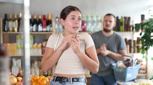  Resentful and upset woman during an argument with her husband in a supermarket. Couple was shopping and quarreled in the store