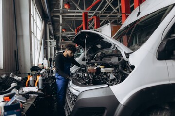 Mechanic repairing engine of white delivery van © Roman