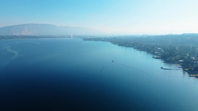 Pan drone shot of Lake Geneva during the day with water fountain in the back in Geneva, Switzerland