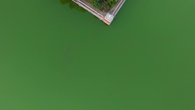Top view of Madurai Theppakulam temple tank with vivid green water and a temple pavilion at the center, forming a minimalistic geometric pattern and artistic landscape in a historic South Indian city.