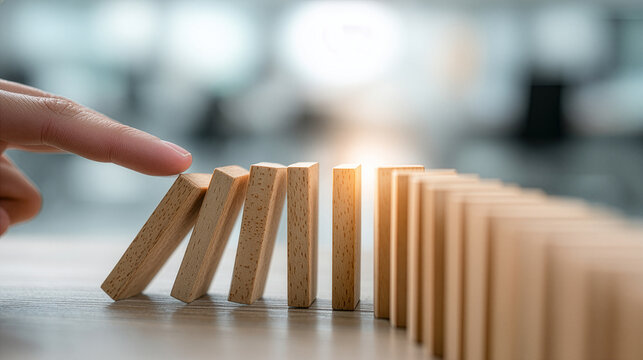 Risk Management Concept With Hand Starting Domino Effect On Desk And Soft Office Blur