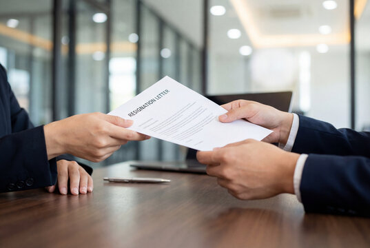 Employee hands handing a printed resignation letter to a manager