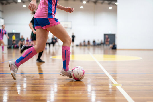 Female futsal player dribbling soccer ball on court action